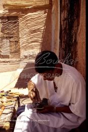 Image du Maroc Professionnelle de  Un artisan marocain fabrique des chaussures, de chapeaux de paille, et de vannerie en raphia, une fabrication artisanale faite main dont la production est très prisée par la population. Son Atelier se situe dans une rue à l'ancienne Kasbah de  Ouarzazate où résident les berbères du sud du Maroc, le Vendredi 22 Août 1997. (Photo / Abdeljalil Bounhar)

